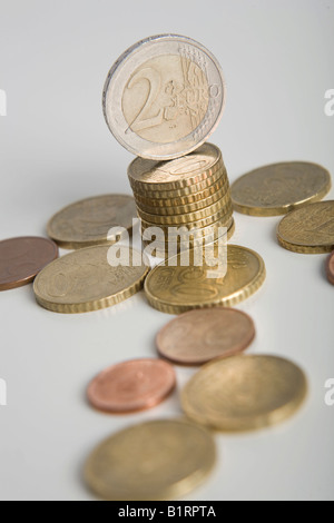 Stacked Euro coins and other coins lying on a table Stock Photo