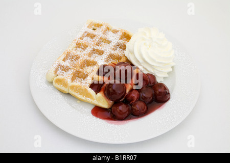 Waffle with powdered sugar, cherries and whipped cream Stock Photo
