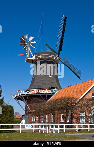 Historical windmill build in typical Dutch style showing the fantail at the back, husking mill, Esens, East Frisia, Lower Saxon Stock Photo