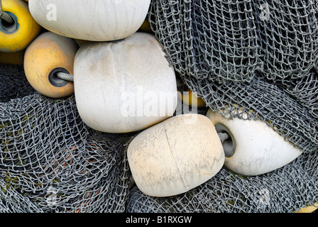 Pile of fishing buoys and green fishing nets, on a quay in port of