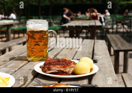 Suckling Pig with Dumplings and a mass of beer served in a beer garden in Taxisgarten, Munich, Bavaria, Germany, Europe Stock Photo