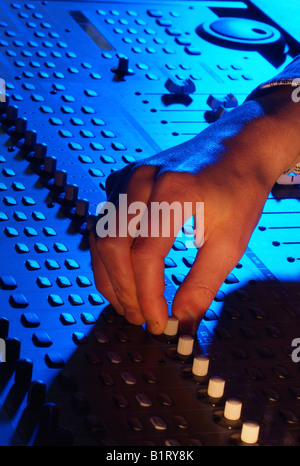 Hands of a sound engineer adjusting the regulators of a professional mixer unit