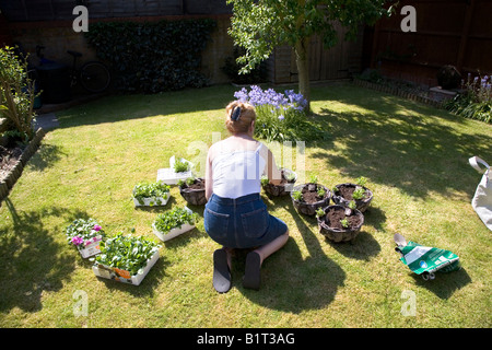 A Woman Kneeling On The Lawn Planting Flowers Stock Photo Alamy