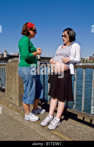 So proud of her pregnancy that she has decorated her protruding belly a young Asian mother to be talks with a friend Stock Photo