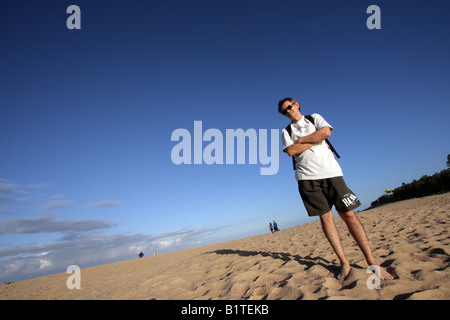 ANGLED PORTRAIT OF A MAN ON A BEACH BLUE SKY BACKGROUND WIDE VIEW HORIZONTAL BDB11156 Stock Photo