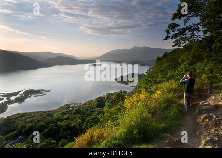 Lady walker looking out over Lake Derwent Water with binoculars from Surprise View in June 2008 Stock Photo