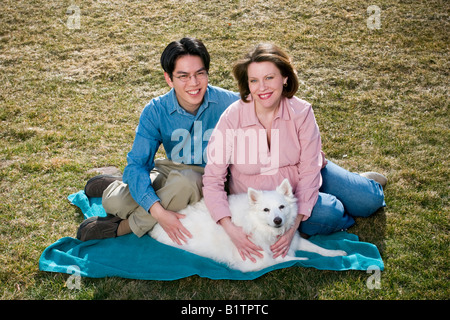 Young married couple Asian man with glasses and pregnant Caucasian woman posing together with their dog Stock Photo