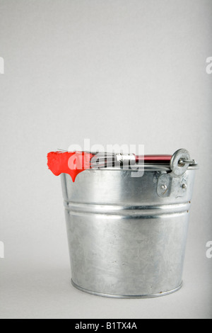 A paint brush loaded with paint resting on a pail Stock Photo