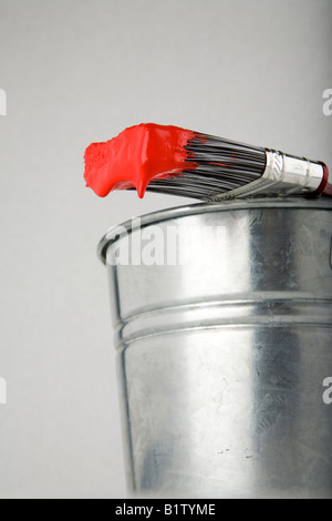 A paint brush loaded with paint resting on a pail Stock Photo