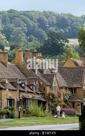 Broadway a northern Cotswold town in Worcestershire England UK Looking toward Fish Hill man mowing grass Stock Photo