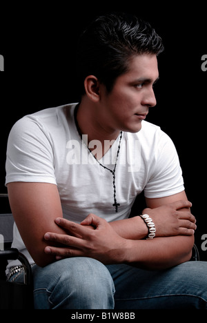 Studio shot of a young man seatting comfortably on a chair, over a black background Stock Photo