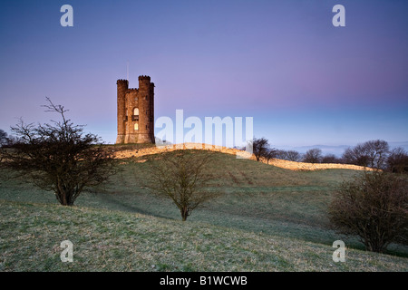 Very famous Broadway Tower overlooking the pituresque village of Broadway.  Early morning with sunrise behind. Stock Photo
