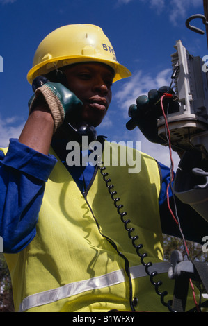 BOTSWANA Southern Africa People Work Portrait of male trainee electrical engineer working on terminal box using telephone Stock Photo