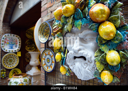 ITALY Tuscany San Gimignano Ceramics shop display of colourful plates and face of bearded man with fruit and vines in his hair Stock Photo