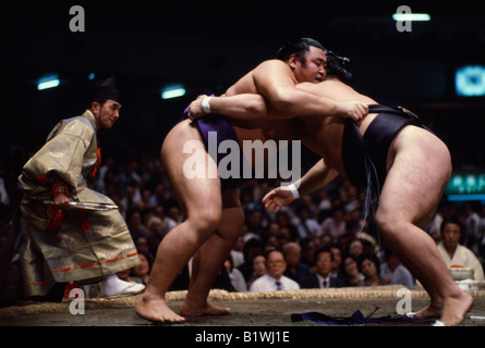 JAPAN Samurai Sumo wrestlers in ring watched by referee wearing the costume of a shogun. Sumo is an ancient form of wrestling Stock Photo