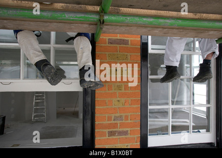 Two workers relax, sitting on some scaffolding. Stock Photo