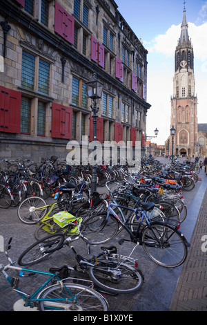 Bicycles – some fallen over – left in a line at the side of the Stadhuis. The Nieuwe Kerk Cathedral is behind. Delft Netherland Stock Photo