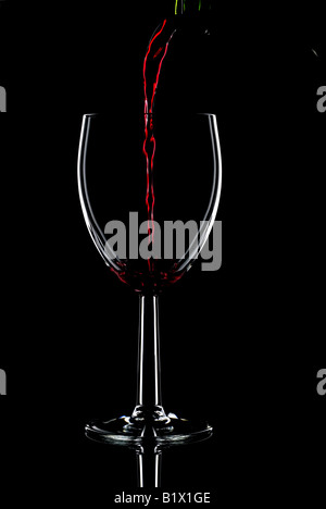 Low key shot of red wine being poured into a glass against a black background Stock Photo