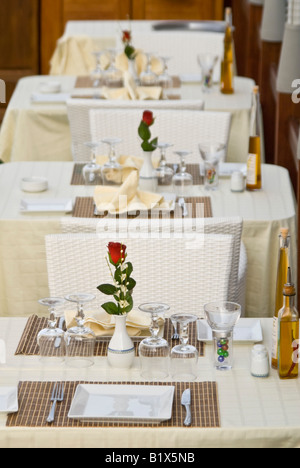 Vertical view of empty tables for two set outside ready for dinner service at an expensive waterside restaurant Stock Photo