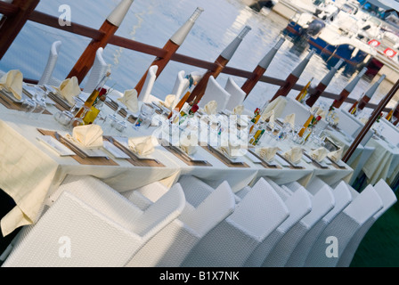 Horizontal angular view of an empty table for a large party set outside ready for dinner service at a waterside restaurant Stock Photo