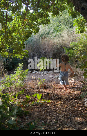 kid going away on a path under a tree Stock Photo