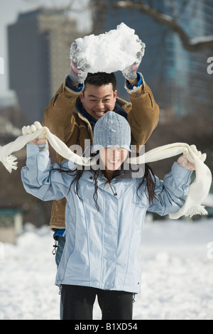 Young man holding up a snowball over a young woman Stock Photo