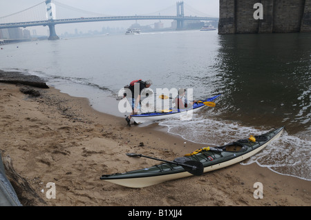 A small beach under the Brooklyn Bridge on the Manhattan side of the East River is a welcome resting place for kayakers. Stock Photo