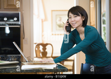 Portrait of a mid adult woman holding a stack of files and talking on a mobile phone Stock Photo