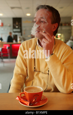 a man smoking a cigarette in a restaurant Stock Photo