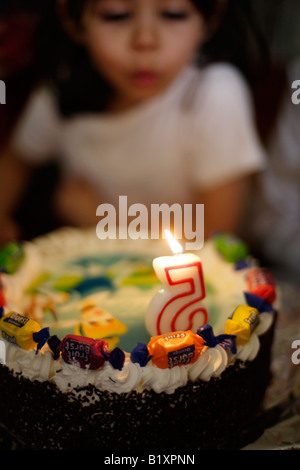 Five year old girl blows out candle on her birthday cake at her party Stock Photo