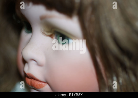 White demure porcelain dolls face close up with green eyes and brunette hair Stock Photo