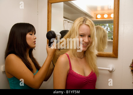 two teenage girls doing each other's hair and makeup Stock Photo