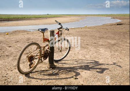 A lone abandoned bike on the banks of the River Glaven at Blakeney, North Norfolk coast Stock Photo