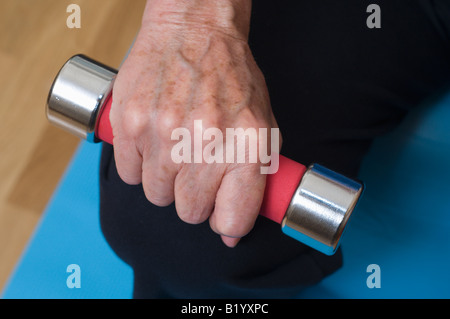 An elderly womans hand with barbell. Stock Photo