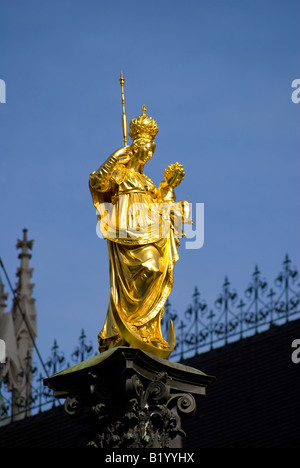 Munich, Bavaria, Germany. Statue of the Virgin Mary on top of the Mariensaule in Marienplatz. Town Hall (Rathaus) behind Stock Photo