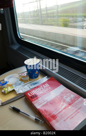 Rail Travel. European Rail Timetable, empty coffee cup and pen by window of train carriage Stock Photo