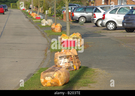 Sorted domestic household rubbish recycle orange sack with glass in red box on grass verge beside concrete road cars on front garden driveway Essex UK Stock Photo