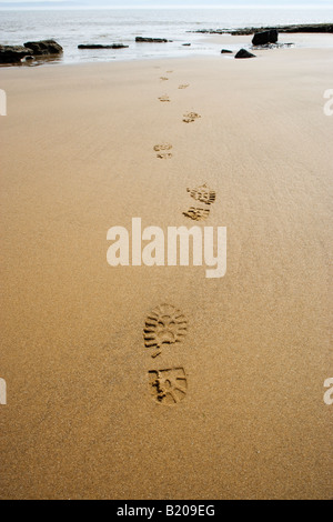 Footprints on beach leading out to sea. UK Stock Photo