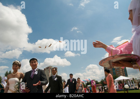 Guest throwing candy over Kazakh brides and grooms during a simultaneously mass wedding ceremony in Arai park in Astana capital of Kazakhstan Stock Photo