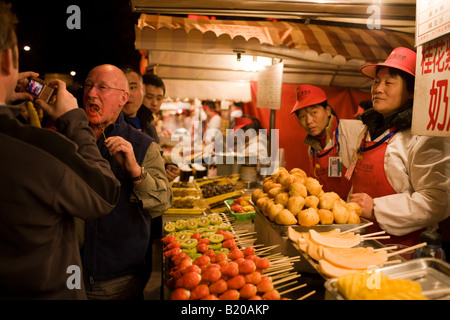 Tourists try Chinese snacks in the Night Market Wangfujing Street Beijing China Stock Photo