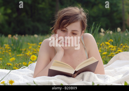 Young woman lying on a meadow, reading Stock Photo