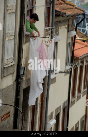 A local resident hangs out the washing to dry, a common sight in the old town of Oporto in Portugal. Stock Photo