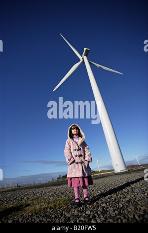 Girl stands beneath a windmill open to visitors at Te Apiti windfarm near Palmerston North Manawatu New Zealand Stock Photo