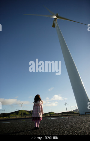 Girl explores a windmill open to visitors and looks up at a towering turbine Stock Photo