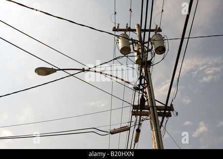 Powerlines converging in a power line pole in town high above the ground. Stock Photo