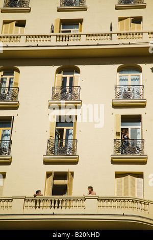 SPAIN Madrid Young woman stand on hostel balcony above two young adult men sitting on balcony Stock Photo