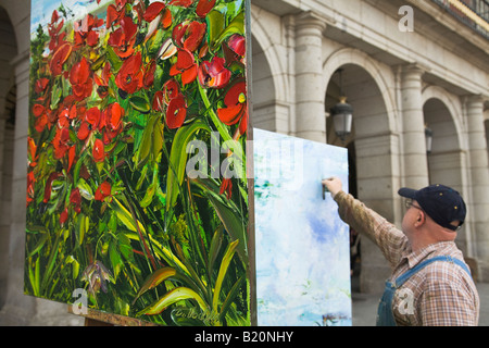 SPAIN Madrid Man painting on canvas in Plaza Mayor completed painting of red poppies on easel Stock Photo