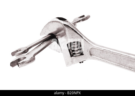 Adjustable wrench gripping a pair of spanners on white background Stock Photo