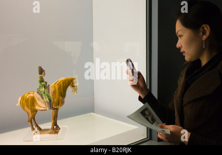 Woman takes a photograph using a mobile phone of an object on display in the Shanghai Museum China Stock Photo
