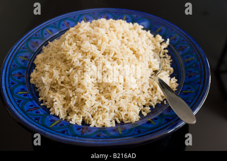 Bowl of brown wholegrain rice and spoon Rice has become an expensive commodity as its in short supply Stock Photo